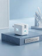 SevenX 35W USB-C Power Adapter with folding plug sitting on a slate blue surface in a bright, modern setting.